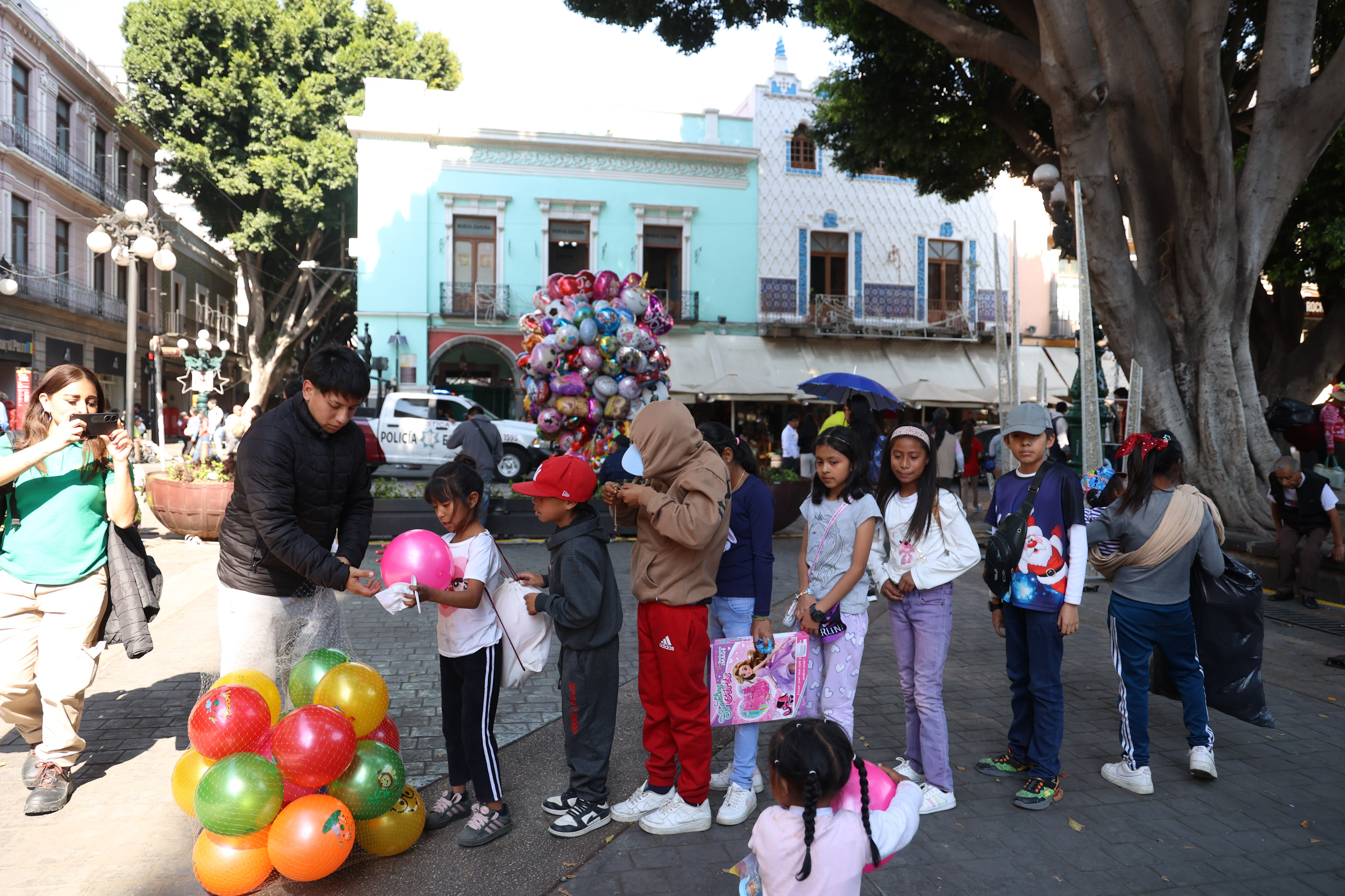 VIDEO Ayudantes de los Reyes Magos regalan juguetes en el zócalo de Puebla