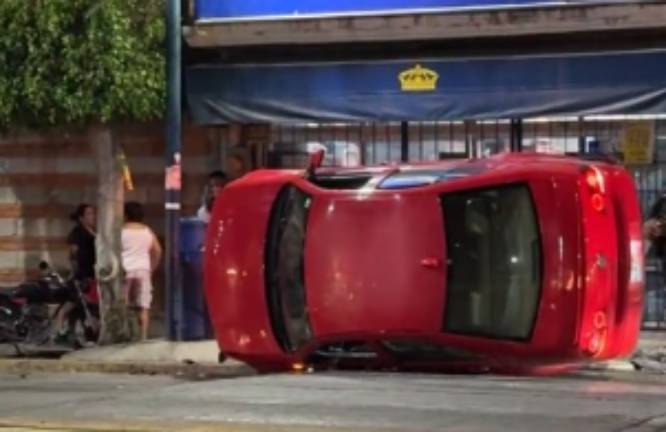 Vuelca automóvil y arrolla a dos personas frente a secundaria en Izúcar