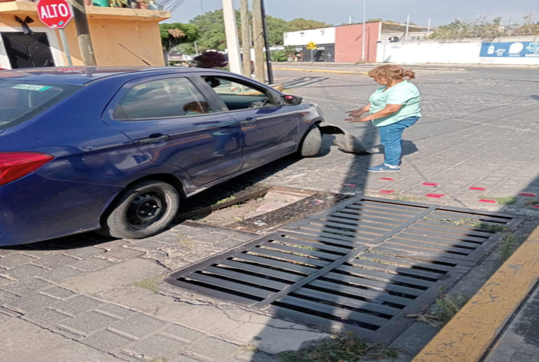 Ciudadana cae con su coche en alcantarilla abierta en Cholula y afecta a su unidad