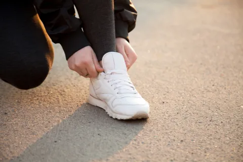 persona-ajustando-tenis-blancos