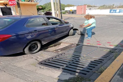 Ciudadana cae con su coche en alcantarilla abierta en Cholula y afecta a su unidad.